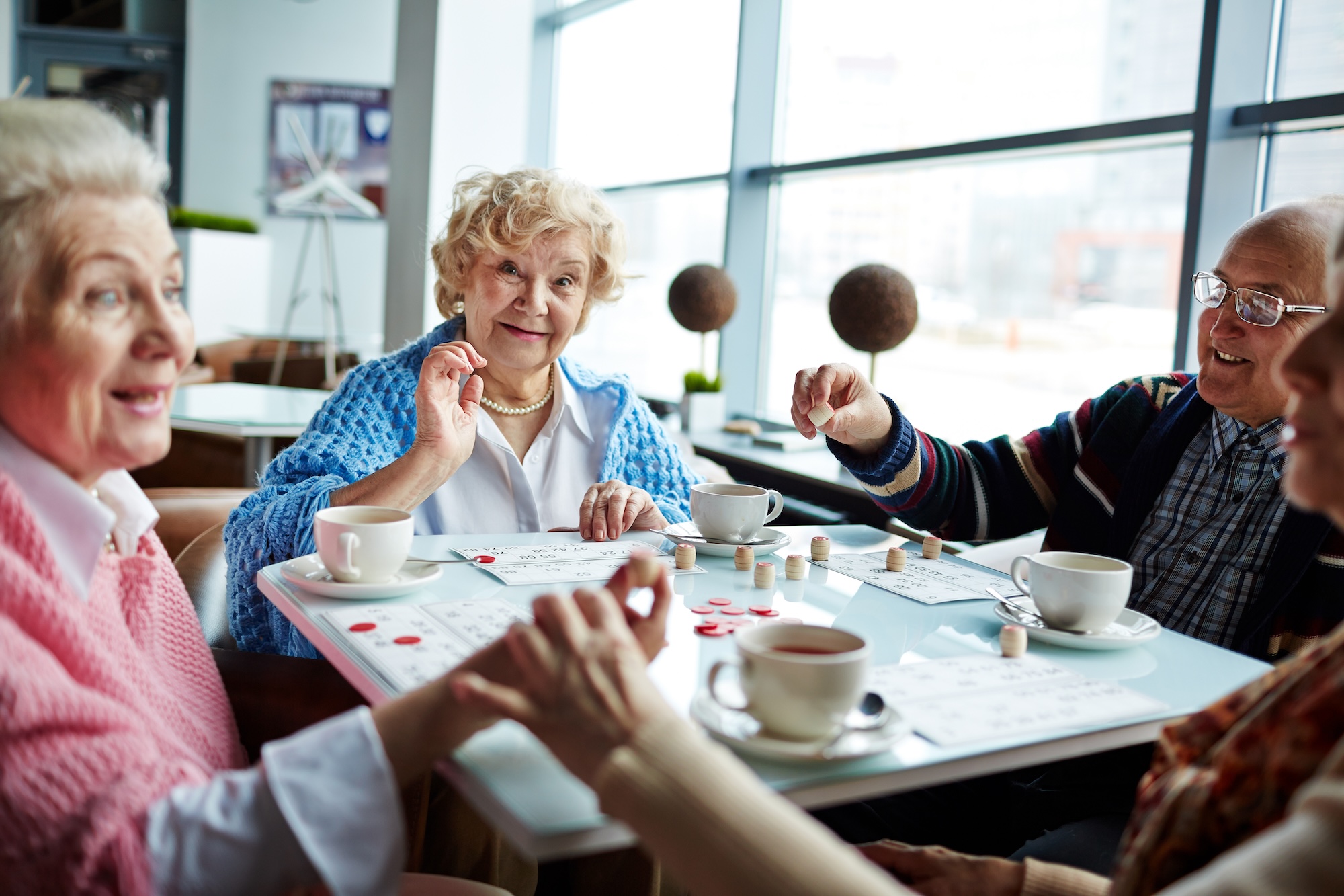 Happy senior man and women playing lotto and having tea